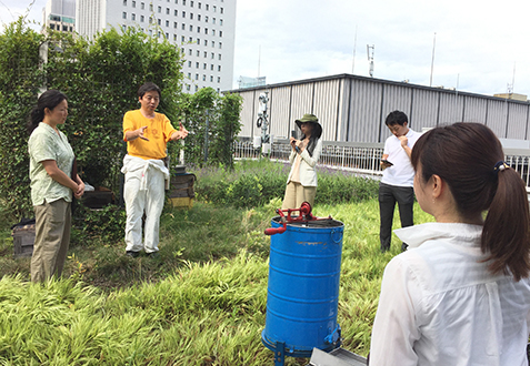 ビルの屋上での養蜂活動を指導する田中さん